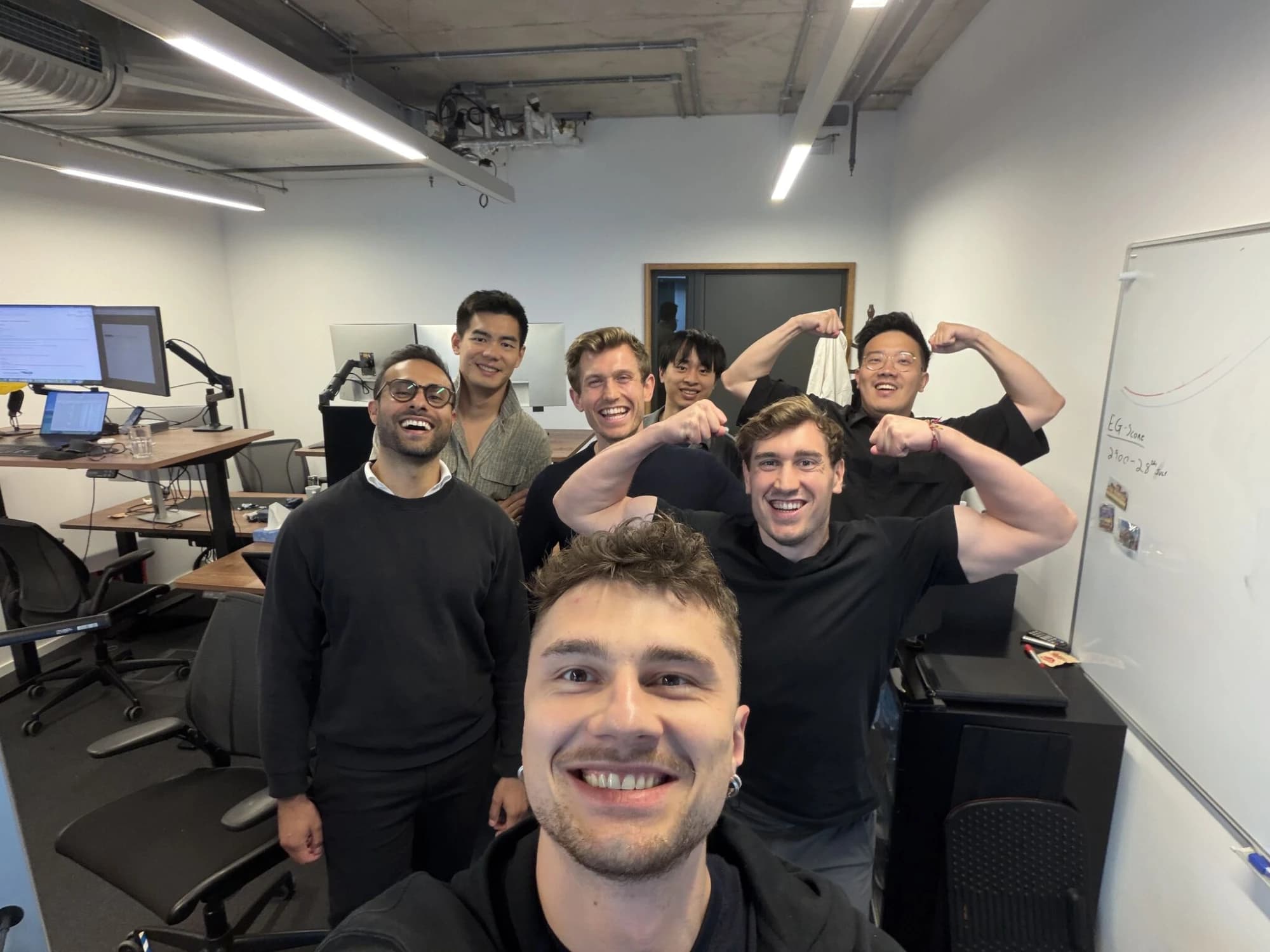 The Zaro team in the office — grinning at the camera, two of them flexing.